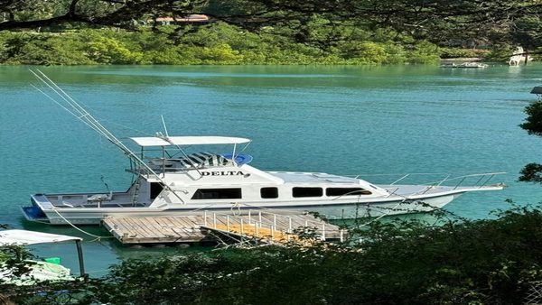 Delta fishing boat moored at a dock on turquoise water, ready for charter
